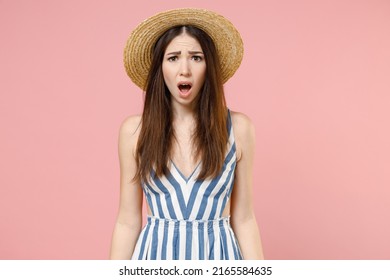 Young amazed impressed astonished caucasian woman in summer clothes striped dress straw hat looking camera with open mouth isolated on pastel pink background studio portrait. People lifestyle concept