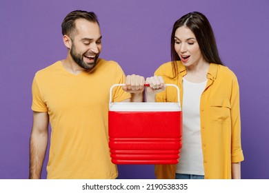 Young Amazed Surprised Fun Cool Couple Two Friends Family Man Woman Together Wear Yellow Casual Clothes Hold Red Box Freezer Cooler Refrigerator Isolated On Plain Violet Background Studio Portrait.