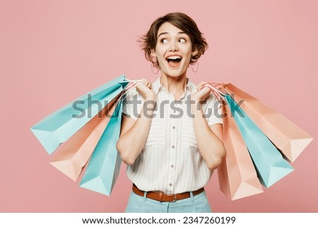 Young amazed surprised shocked woman wear casual clothes hold shopping paper package bags look aside on area isolated on plain pastel pink color background studio. Black Friday sale buy day concept