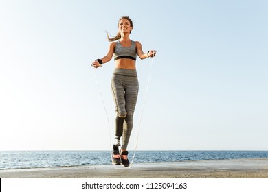 Young amazing happy disabled sports woman jumping with skipping rope on the beach outdoors. - Powered by Shutterstock