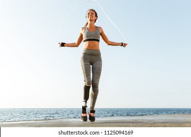 Young amazing happy disabled sports woman jumping with skipping rope on the beach outdoors. - Powered by Shutterstock