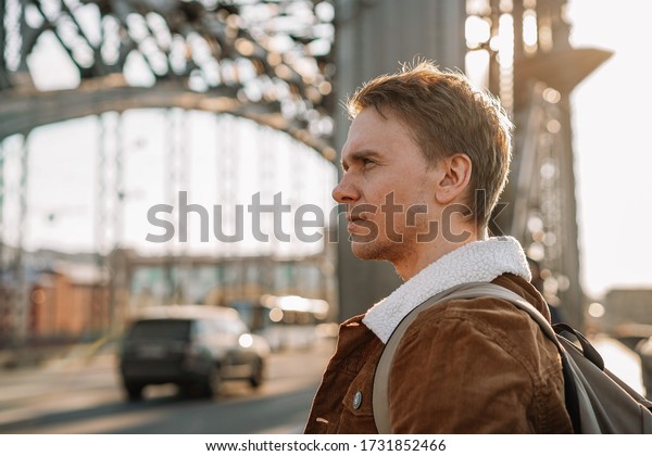 A young ambitious\
business man walks along the streets, a metal bridge in a Sunny\
beautiful sunset