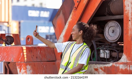 Young American African Female Trainee Uses Mobile Phone For Social Connection During Her Break Time At A Logistic Cargo Or Shipping Warehouse