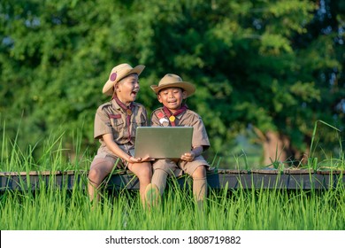 Young American Boy Scouts Use Laptop At Scout Camp During Their Summer Camp.