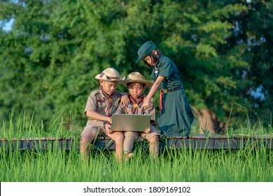 Young American Boy Scouts Use Laptop At Scout Camp During Their Summer Camp.