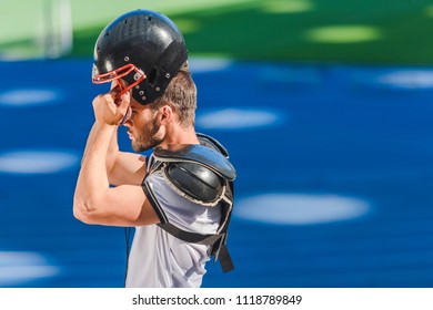 Young American Football Player Putting On Helmet At Sports Stadium