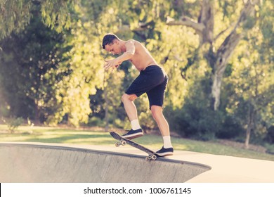 Young American Man In Naked Torso Practicing Radical Skate Board Jumping And Enjoying Tricks And Stunts In Concrete Half Pipe Skating Track In Sport And Healthy Lifestyle Concept