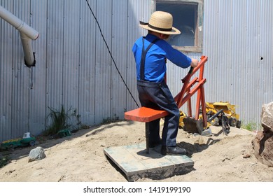 Young Amish Boy Playing On A Toy Back Hoe