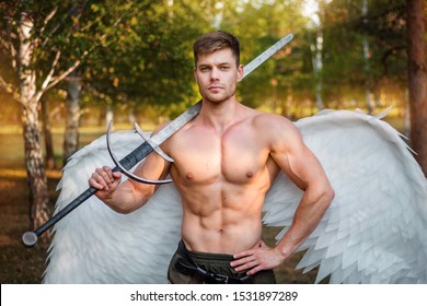 A young angel, a bodybuilder in plate armor on his legs with wings behind his back, holds in his hands a two-handed sword.