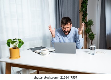 Young Angry And Frustrated Freelancer Businessman Sitting In An Home Office With A Laptop And Is Furious At The Noise Made By The Workers Upstairs Because He Can't Work On His Project