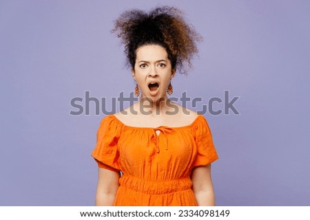 Young angry mad furious latin woman she wear orange blouse casual clothes look camera with opened mouth scream shout isolated on plain pastel light purple background studio portrait. Lifestyle concept