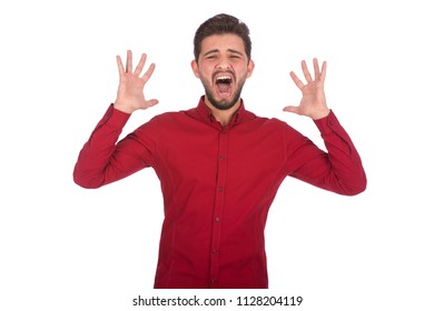 young angry man screaming while rising hands up , wearing red shirt, isolated on white background