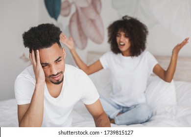 Young Angry Sad Irritated Frustrated African Swearing Screaming Couple Girl Guy In White T-shirts Sitting On Bed Indoors In Bedroom At Home Spend Time In Room. Bad Mood Quarantine Lifestyle Concept