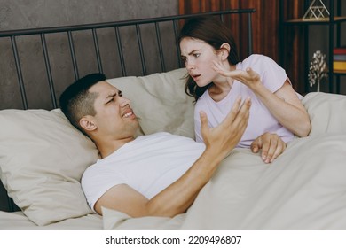 Young Angry Sad Mad Dissatisfied Displeased Couple Two Family Man Woman She He Wearing T-shirt Pajama Arguing Lying In Bed Spend Time Together In Bedroom Home In Own Room Hotel. Real Estate Concept