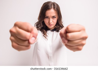 Young and angry woman is clenching her fists in rage.