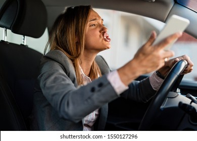 Young Angry Woman Driving A Car And Yelling At Someone While Being Stuck In Traffic Jam. 