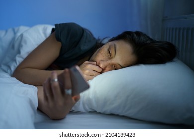 Young Anxious Asian Woman Lying In Bed Staring At Smartphone Screen At Night, Reading About Depression Symptoms In Internet, Phone Addicted Female Can Not Stop Scrolling Social Media Before Bedtime