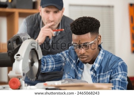 young apprentice learning to use circular saw