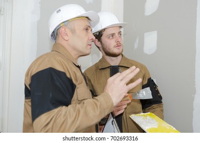 Young Apprentice With Professional Plasterer