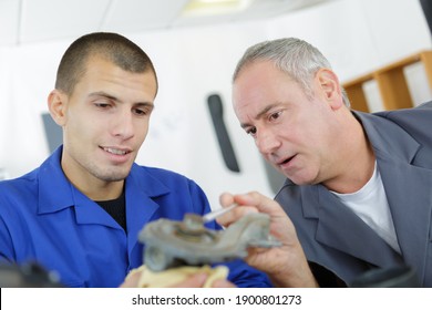 young apprentice with teacher working on piece of metal