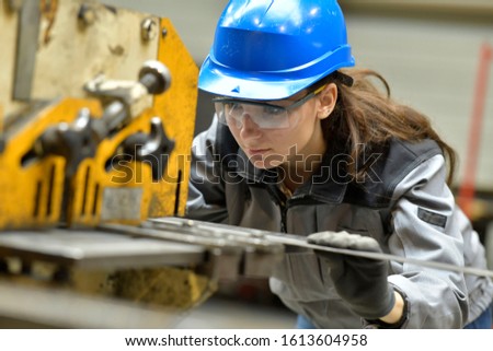 Young apprentice using steelworks machine
