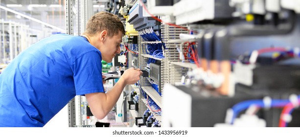 Young Apprentice Worker In An Industrial Company Assembling Electronic Components In The Mechanical Engineering Of A Modern Factory 