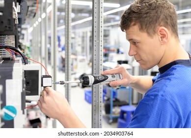 Young Apprentice Worker In An Industrial Company Assembling Electronic Components In The Mechanical Engineering Of A Modern Factory 