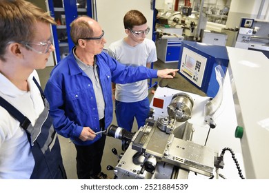 young apprentices in technical vocational training are taught by older trainers on a cnc lathes machine - Powered by Shutterstock