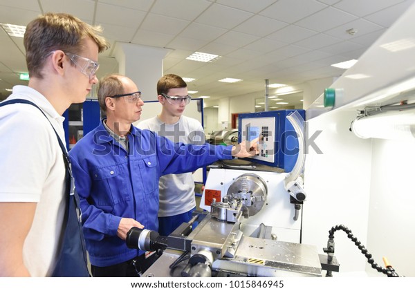 young apprentices in\
technical vocational training are taught by older trainers on a cnc\
lathes machine