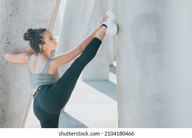 Young arab african woman on training sport wear leggins and stretching his legs on karate position and gymnastics. Serious looking to camera, young athlete urban city background - Powered by Shutterstock