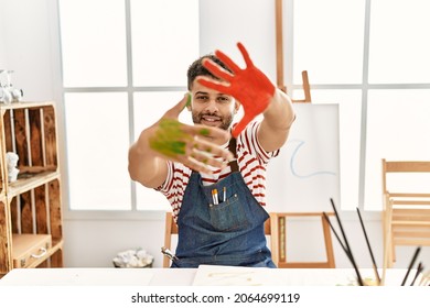 Young arab artist man smiling happy showing painted hands at art studio.
