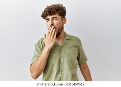 Young Arab Doctor Man Standing Over Isolated Background Bored Yawning Tired Covering Mouth With Hand. Restless And Sleepiness. 