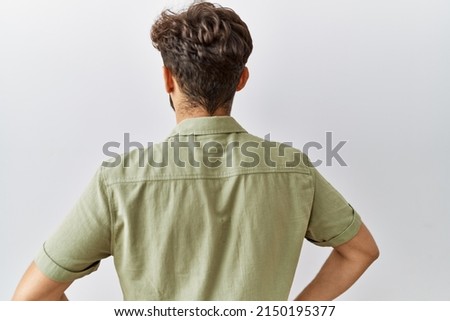 Young arab doctor man standing over isolated background standing backwards looking away with arms on body 
