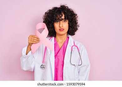 Young Arab Doctor Woman With Curly Hair Holding Cancer Ribbon Over Isolated Pink Background With A Confident Expression On Smart Face Thinking Serious