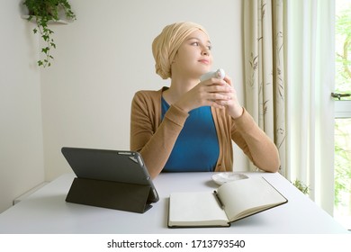 Young Arab Emirati Girl At Home Wearing Turban. Middle Eastern Woman On Hijab Working At Home Or Home Schooling Concept During Pandemic Epidemic Spread Outbreak Lock Down. Happy Staying At Home