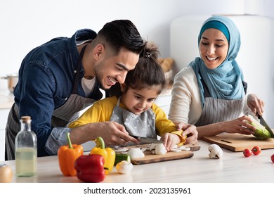 Young Arab Father Showing How To Chop Mushrooms To His Little Daughter While They Cooking Healthy Tasty Food Together At Home, Happy Muslim Family Of Three Enjoying Preparing Vegetarian Meal