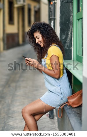 Similar – Frau mit Afro-Haaren auf der Straße, die ein Smartphone hält.