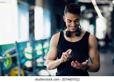 Young Arab Male Athlete Applying Sanitizer Spray On Hands Before Training In Gym, Middle Eastern Man Following Safety Measures Against Covid-19 While Exercising In Modern Sport Club, Copy Space - Powered by Shutterstock