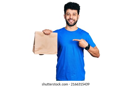 Young Arab Man With Beard Holding Take Away Paper Bag Smiling Happy Pointing With Hand And Finger 