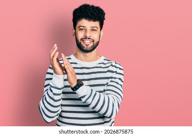 Young Arab Man With Beard Wearing Casual Striped Sweater Clapping And Applauding Happy And Joyful, Smiling Proud Hands Together 