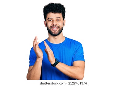 Young Arab Man With Beard Wearing Casual Blue T Shirt Clapping And Applauding Happy And Joyful, Smiling Proud Hands Together 