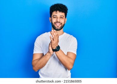 Young Arab Man With Beard Wearing Casual White T Shirt Clapping And Applauding Happy And Joyful, Smiling Proud Hands Together 