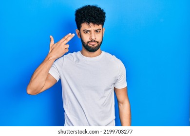 Young Arab Man With Beard Wearing Casual White T Shirt Shooting And Killing Oneself Pointing Hand And Fingers To Head Like Gun, Suicide Gesture. 