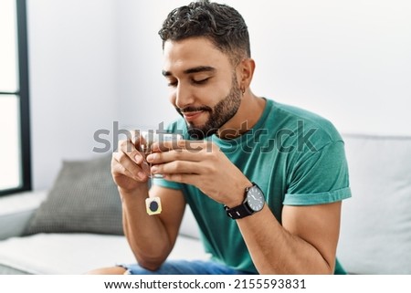 Young arab man drinking tea sitting on sofa at home