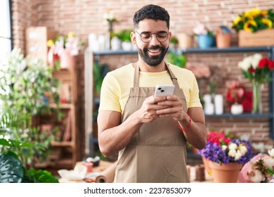 Young arab man florist smiling confident using smartphone at florist - Powered by Shutterstock