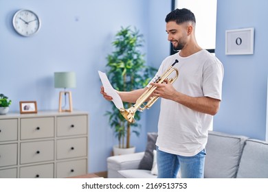 Young Arab Man Musician Holding Trumpet And Music Sheet At Home