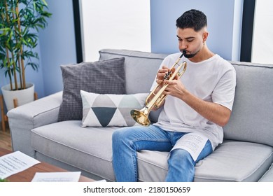 Young Arab Man Musician Playing Trumpet Sitting On Sofa At Home