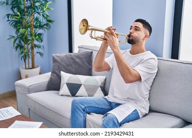 Young Arab Man Musician Playing Trumpet Sitting On Sofa At Home