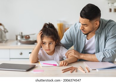 Young Arab Man Single Father Comforting His Upset Little Daughter, Sitting At Table With Colorful Pencils And Notebook At Kitchen, Bored Girl Kid With Unhappy Face Expression Looking At Copy Space