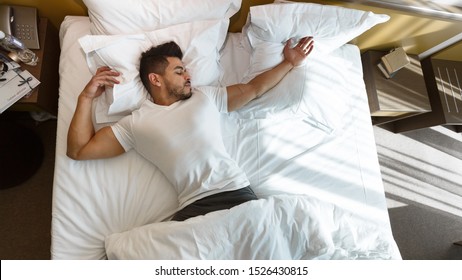 Young Arab Man Sleeping In Bed Alone, Staying In Hotel, Top View, Copy Space